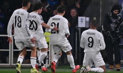 Celebration scene as soccer players rejoice after a goal, featuring Mbappe and his teammates in white kits.