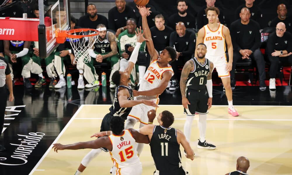 Intense moment in a basketball game with an Atlanta Hawks player scoring a layup against the Milwaukee Bucks.