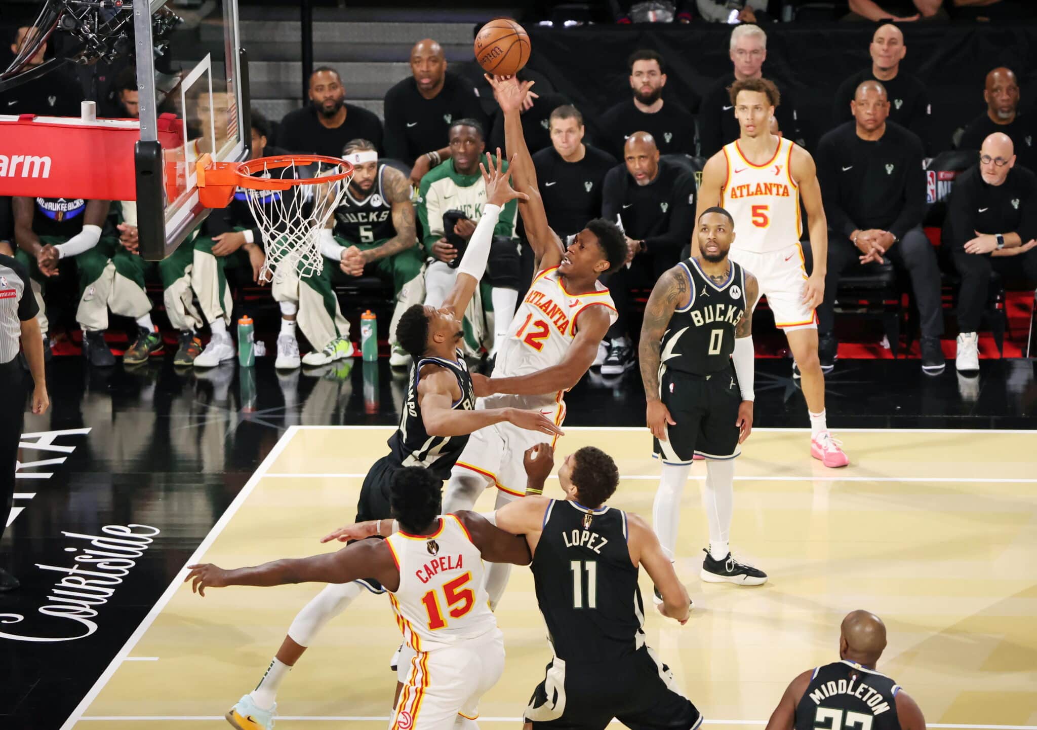 Intense moment in a basketball game with an Atlanta Hawks player scoring a layup against the Milwaukee Bucks.