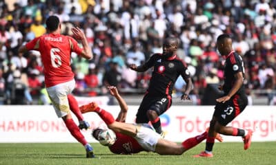 Intense soccer action showing an Orlando Pirates player tackling an opponent during a match.