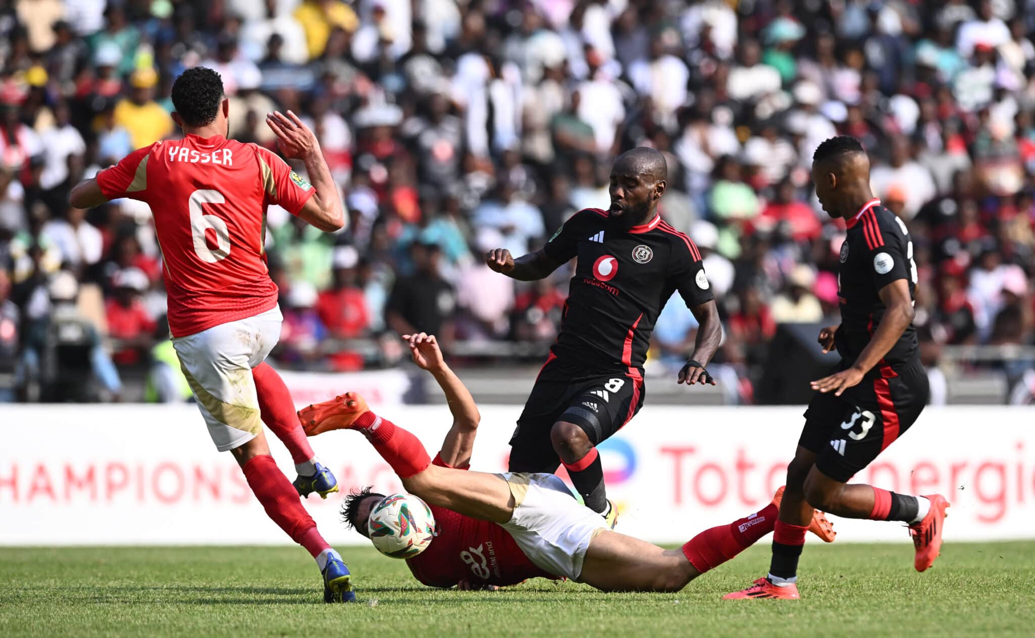 Intense soccer action showing an Orlando Pirates player tackling an opponent during a match.