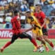 Dynamic action during a football match featuring Kaizer Chiefs and a rival team, with players intensely contesting the ball.